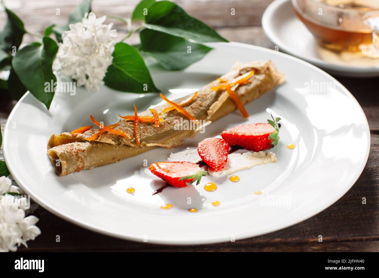 Gerollter Pfannkuchen mit Erdbeere auf weißem Teller Stockfoto