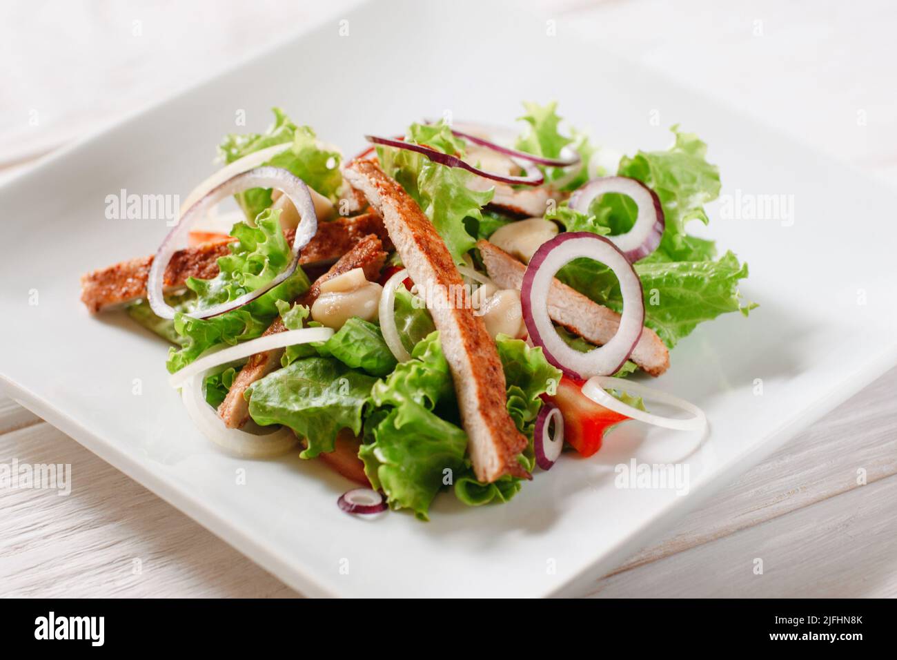 Salat mit Huhn und Pilzen auf weißem Teller Stockfoto