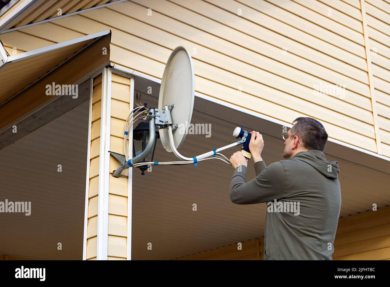 Reparieren TV-Satellitenschüssel, zieht Hausbesitzer Verbindungsmuttern. Stockfoto