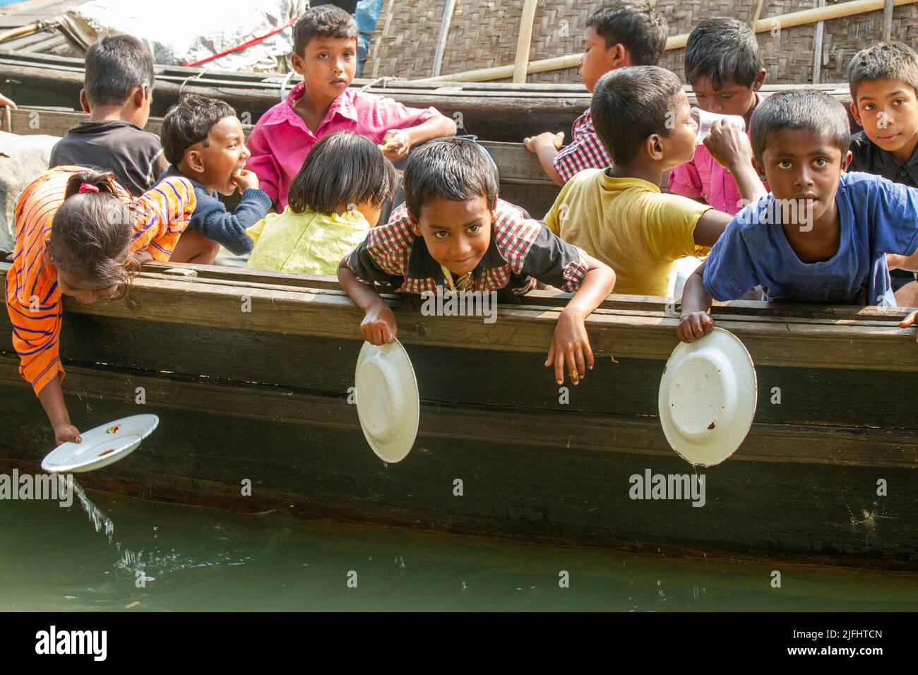 Zigeunerkinder waschen Teller, nachdem sie in einer schwimmenden Schule auf einem Kanal in Sahapur in Sonargaon, Narayanganj, Bangladesch, gegessen haben. Stockfoto