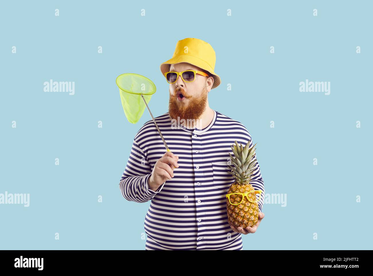 Lustig überrascht Mann mit Ananas und mit Insektennetz isoliert auf Sommer hellblauen Hintergrund. Stockfoto