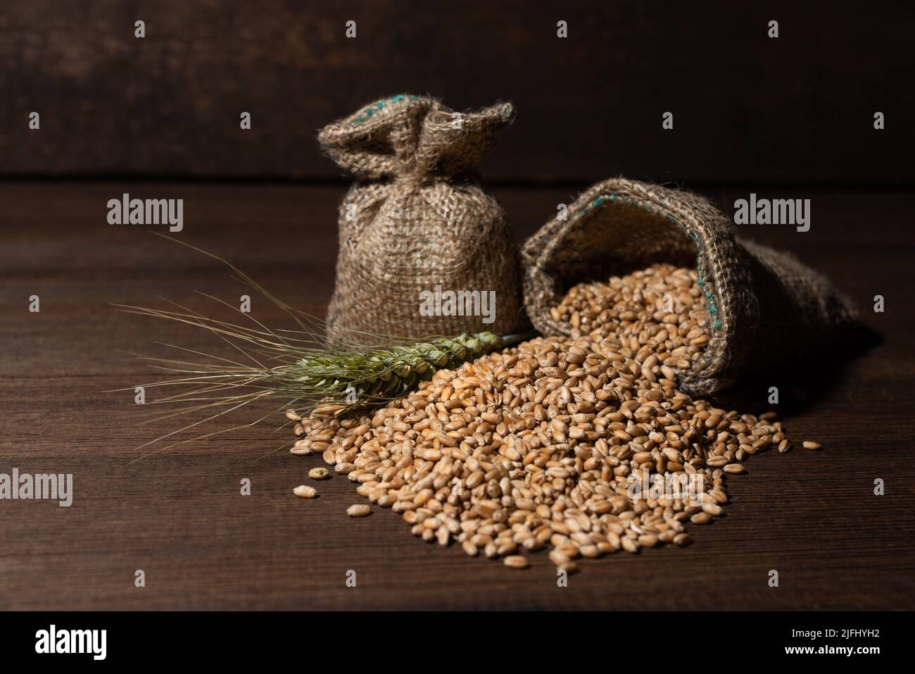Weizenohr und Korn in Sacktuch, auf einem hölzernen Hintergrund. Stockfoto
