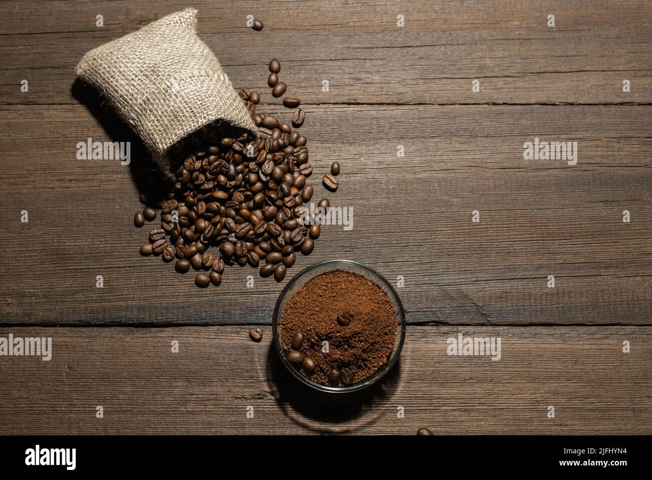 Körner von frisch geröstetem Kaffee und gemahlenem Kaffee auf einem hölzernen Hintergrund. Die Textur von Kaffeebohnen. Stockfoto