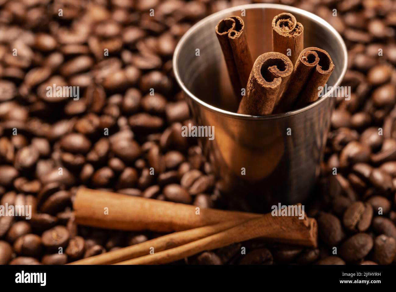 Dekorativer Eimer aus nächster Nähe mit Zimtstangen auf einem Hintergrund von Kaffeebohnen Stockfoto