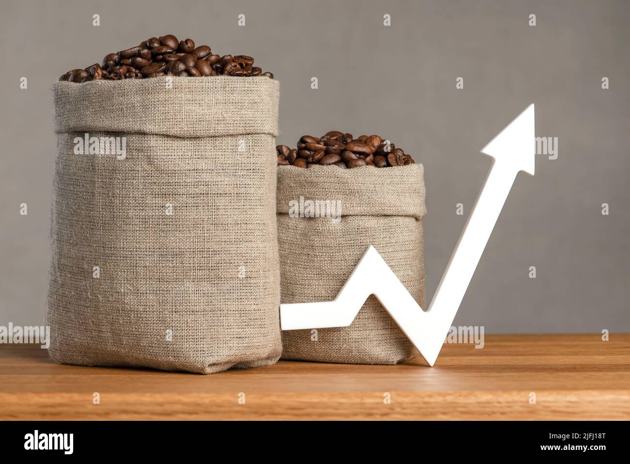 Eine Tüte Kaffeebohnen und ein Pfeil nach oben. Die Kosten für Kaffee auf den Märkten der Welt. Das Konzept des Wachstums der Kosten für Kaffee Stockfoto