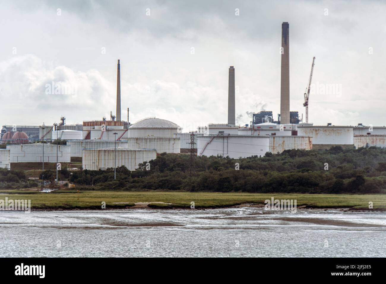 Kamine und Öllagertanker in der ChemicalX Ölraffinerie in Fawley, Southampton, England, Blick vom Boot. Stockfoto