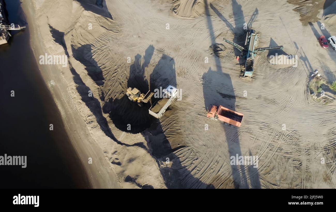 Luftaufnahme von Lastwagen und Maschinen im Sandbruch. Szene. Sandgrube, Ladewagen Sand, Konzept der Schwerindustrie. Stockfoto