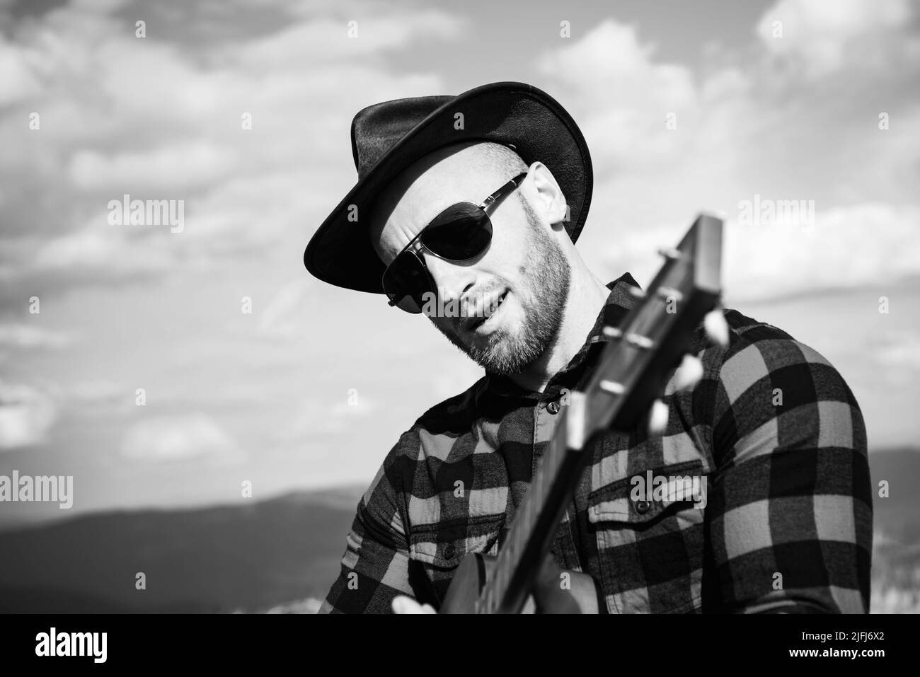 Lässiger Mann, Lifestyle. Nahaufnahme eines Porträts von Cowboy-Western-Männern, die auf der Gitarre spielen. Lifestyle-Wanderkonzept Stockfoto