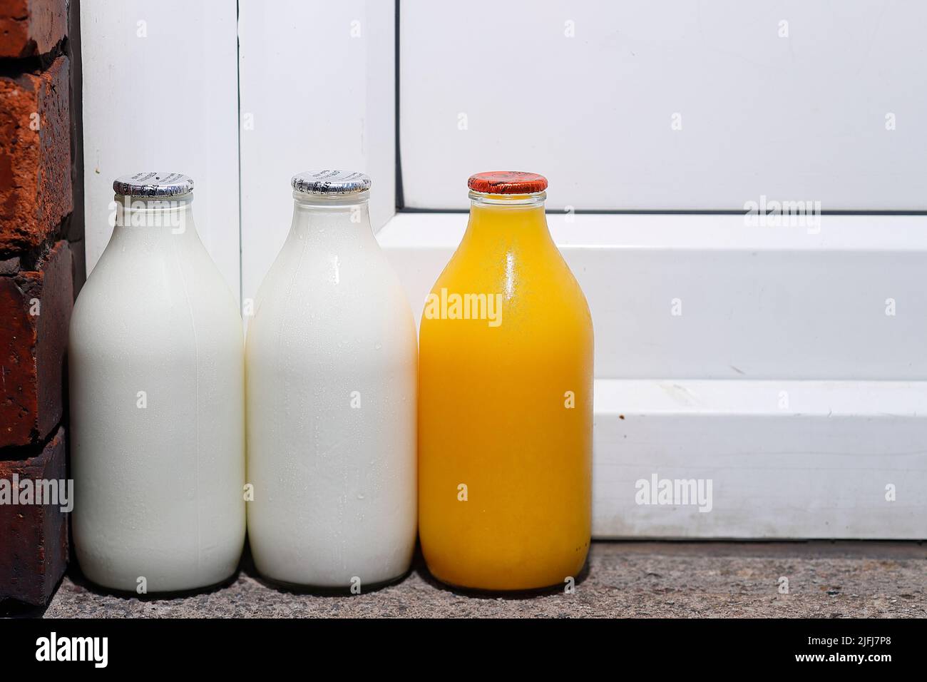 Ein Pint Milch und ein Pint frisch gepressten Orangensaft vor der Haustür, der von einem Milchmann geliefert wird Stockfoto