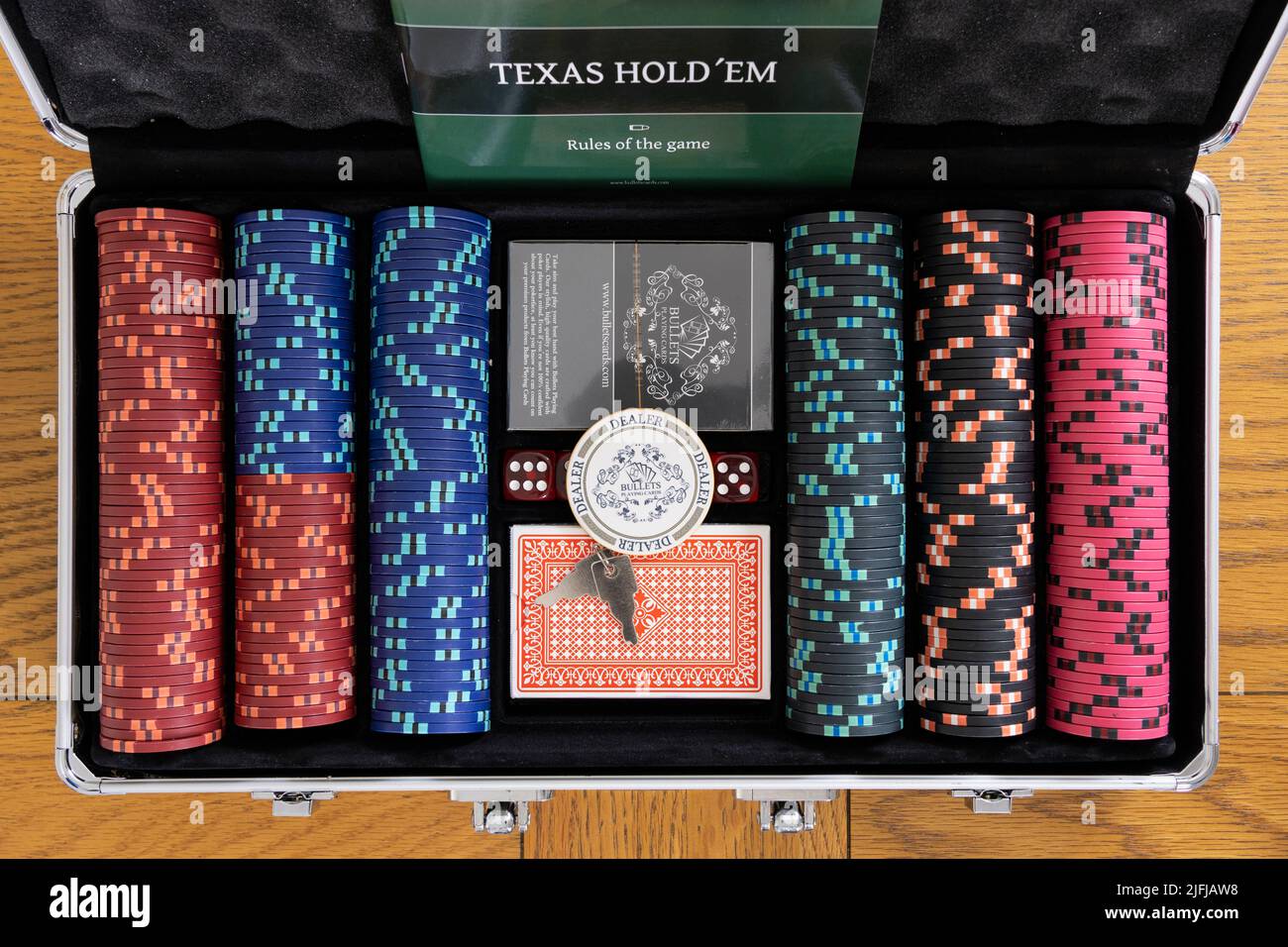 Ein metallischer Pokerkoffer mit Wettchips, Spielkarten und einem Dealer-Token für Texas Hold'em. Thema - Poker, Glücksspiel zu Hause Stockfoto