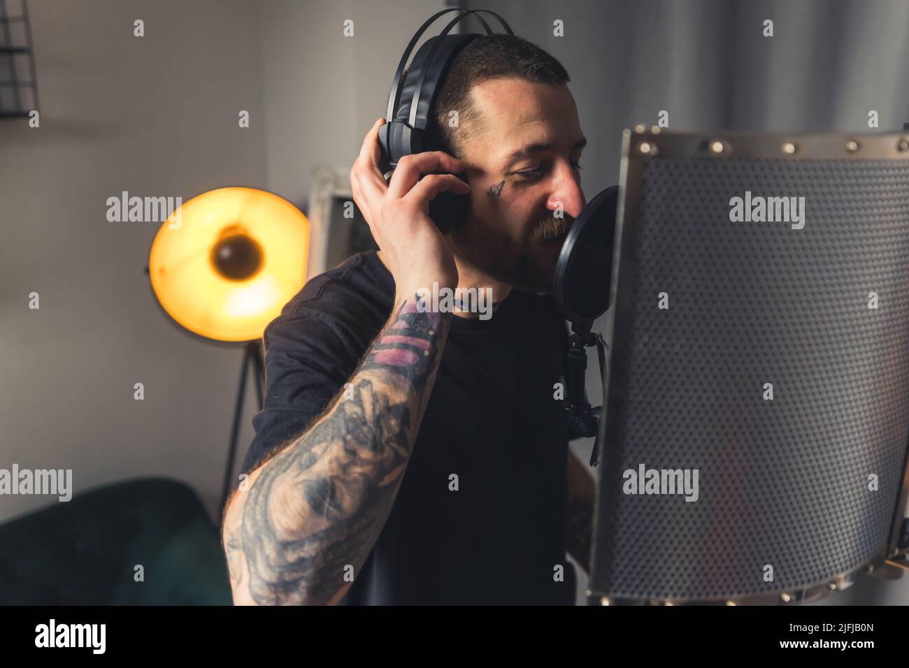 Junge tätowierte Sänger nimmt Musik mit Mikrofon und Kopfhörer Medium Schuss Kopie Raum. Hochwertige Fotos Stockfoto
