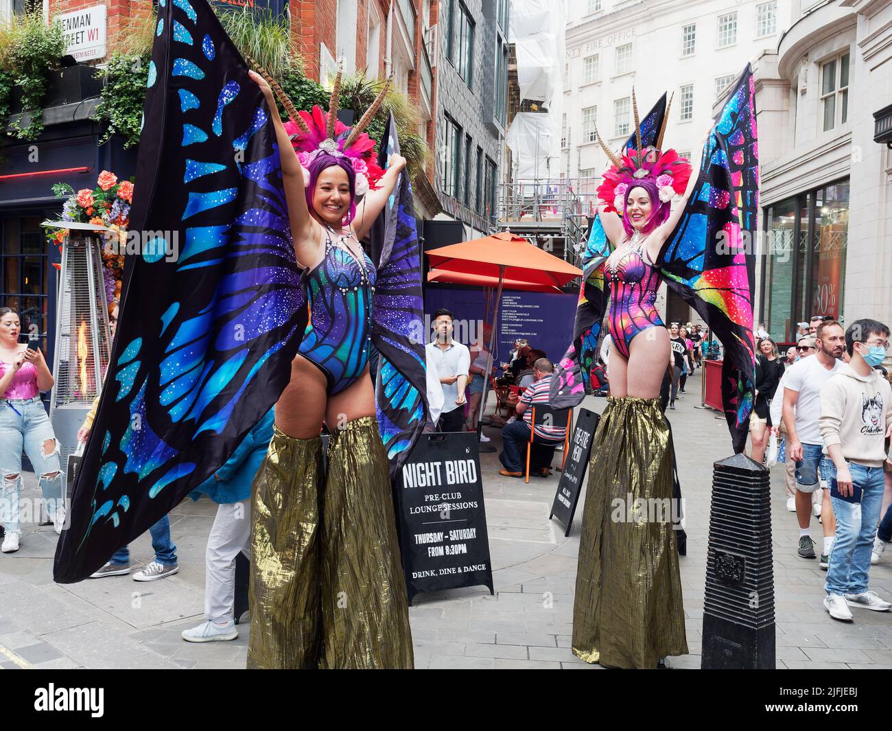 Damen in farbenfrohen Kostümen vor dem Coqbull Soho Restaurant in der Denman Street während der Pride in London Feiern im Jahr 2022 Stockfoto