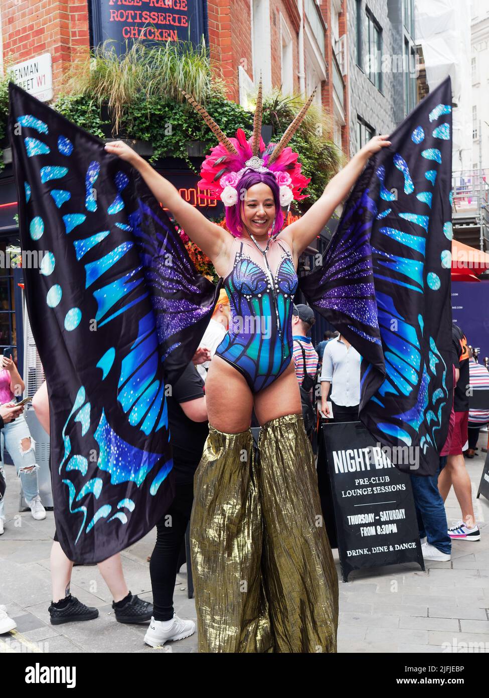 Eine Dame in einem farbenfrohen Kostüm vor dem Coqbull Soho Restaurant in der Denman Street während der Pride in London Feiern im Jahr 2022 Stockfoto