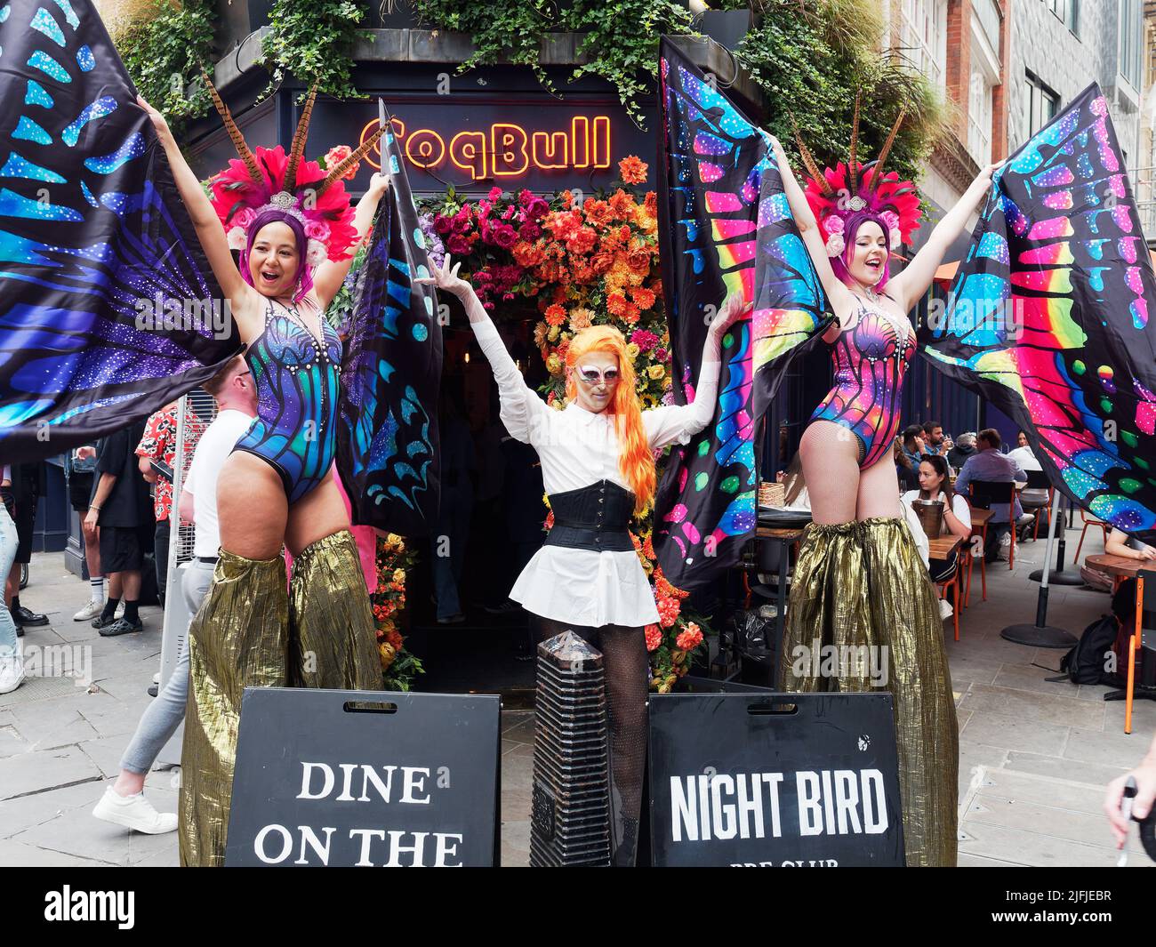 Damen in farbenfrohen Kostümen vor dem Coqbull Soho Restaurant in der Denman Street während der Pride in London Feiern im Jahr 2022 Stockfoto