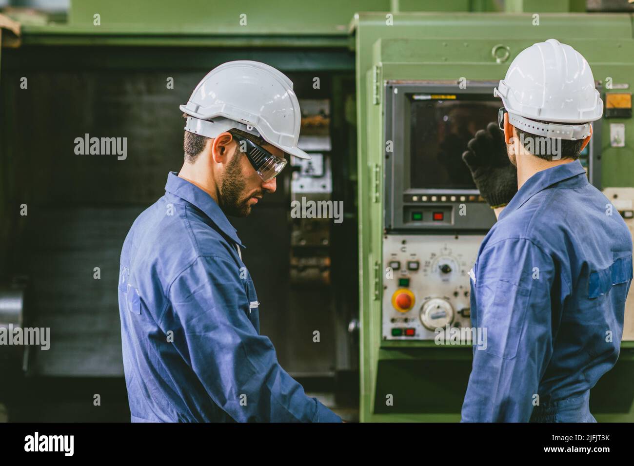 Erfahrene Techniker Mitarbeiter arbeiten zusammen in Metallfabrik bedienen Setup CNC-Maschine. Stockfoto