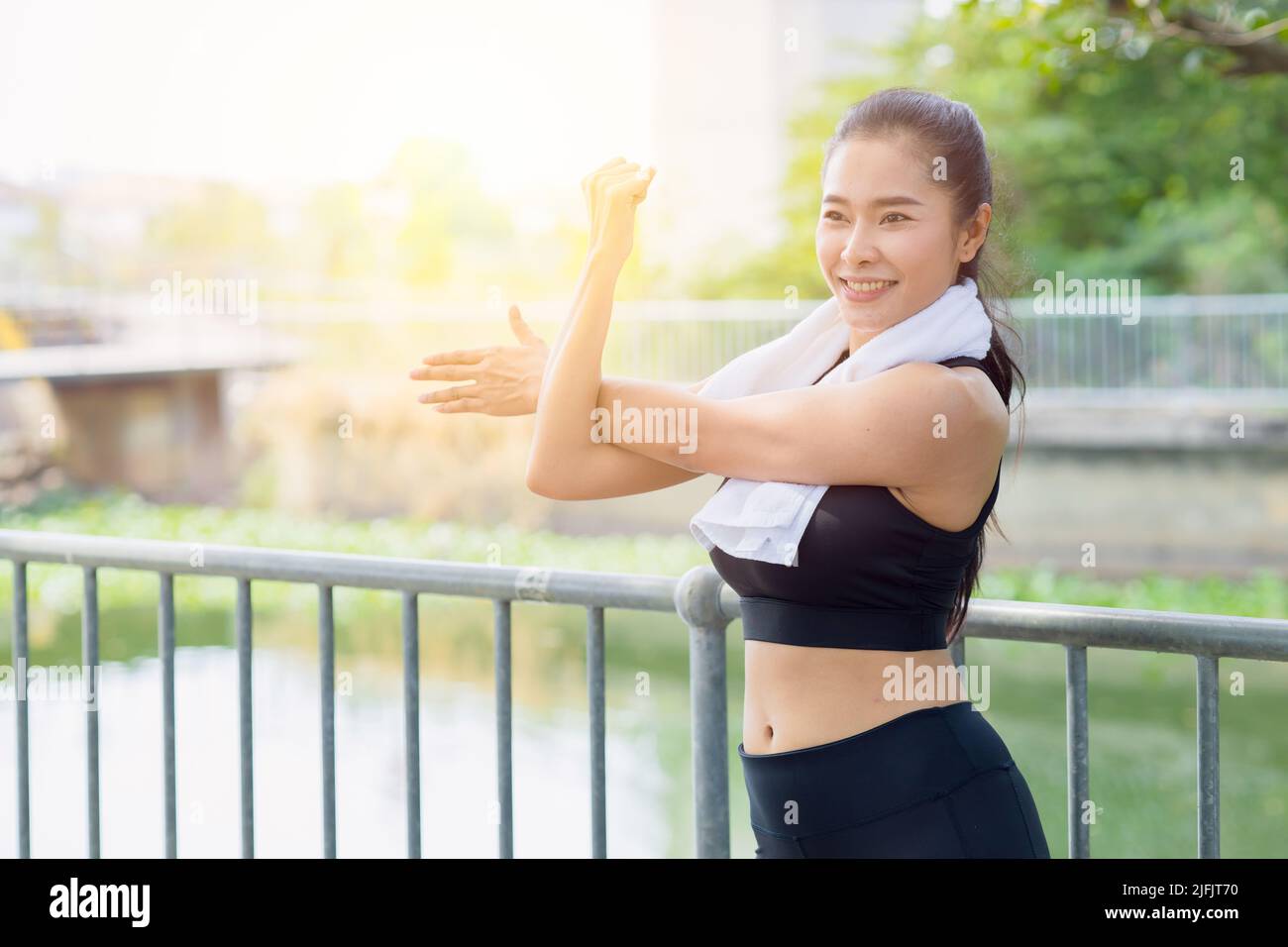 Asiatische gesunde Frau Schulter Stretching Übung im Park am Morgen im Freien Stockfoto