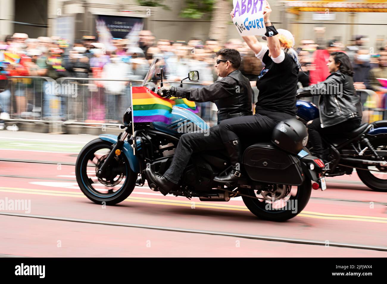 Biker protestieren gegen die Entscheidung des Obersten Gerichtshofs über Abtreibung, indem sie ein Schild hochhalten, während sie an der Pride Parade teilnehmen und auf einem Motorrad fahren. Stockfoto