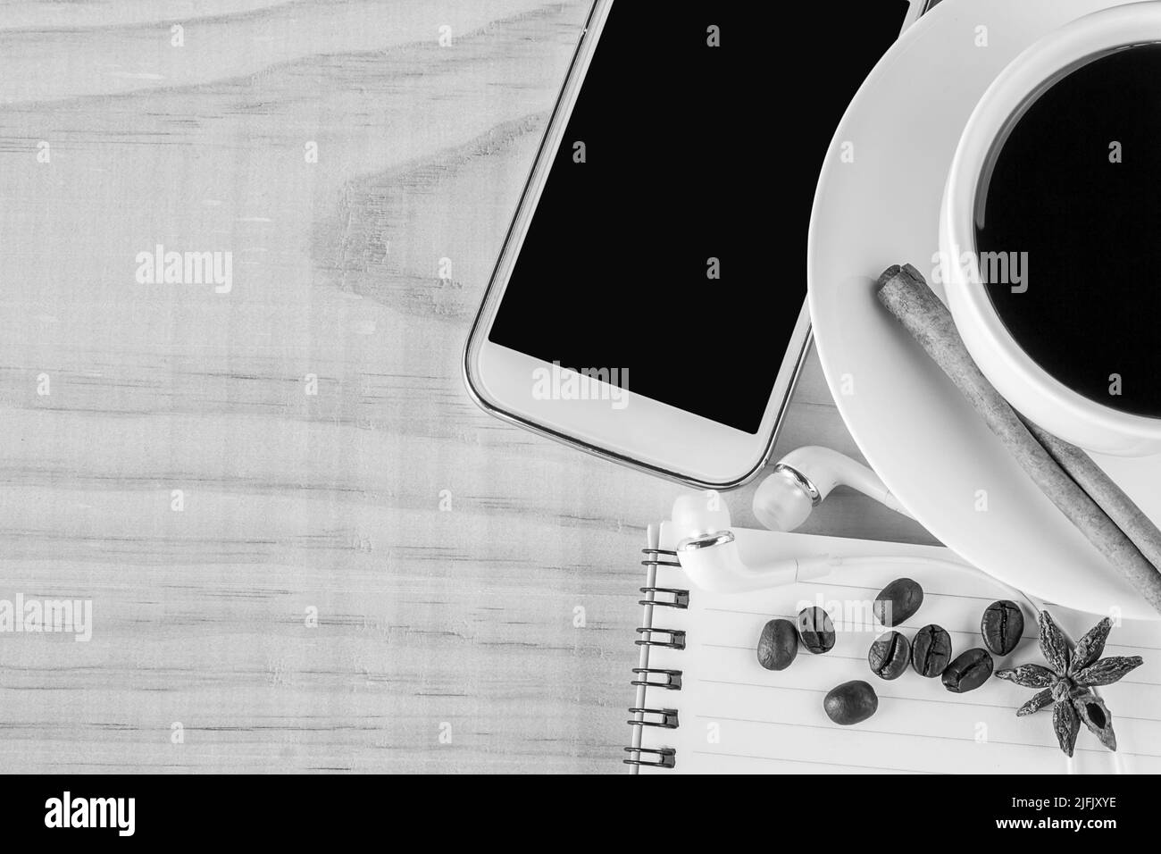 Kaffee und offenes Notizbuch mit Kaffeebohnen auf Holztischhintergrund. Draufsicht mit Kopierplatz. Schwarz-Weiß-Ton Stockfoto