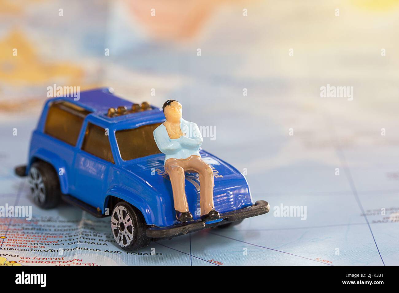 Miniatur-Menschen: Geschäftsmann sitzt auf blauem Auto für die Reise um die Welt mit Wort Karte Hintergrund.Erde Hintergrund Konzept. Stockfoto