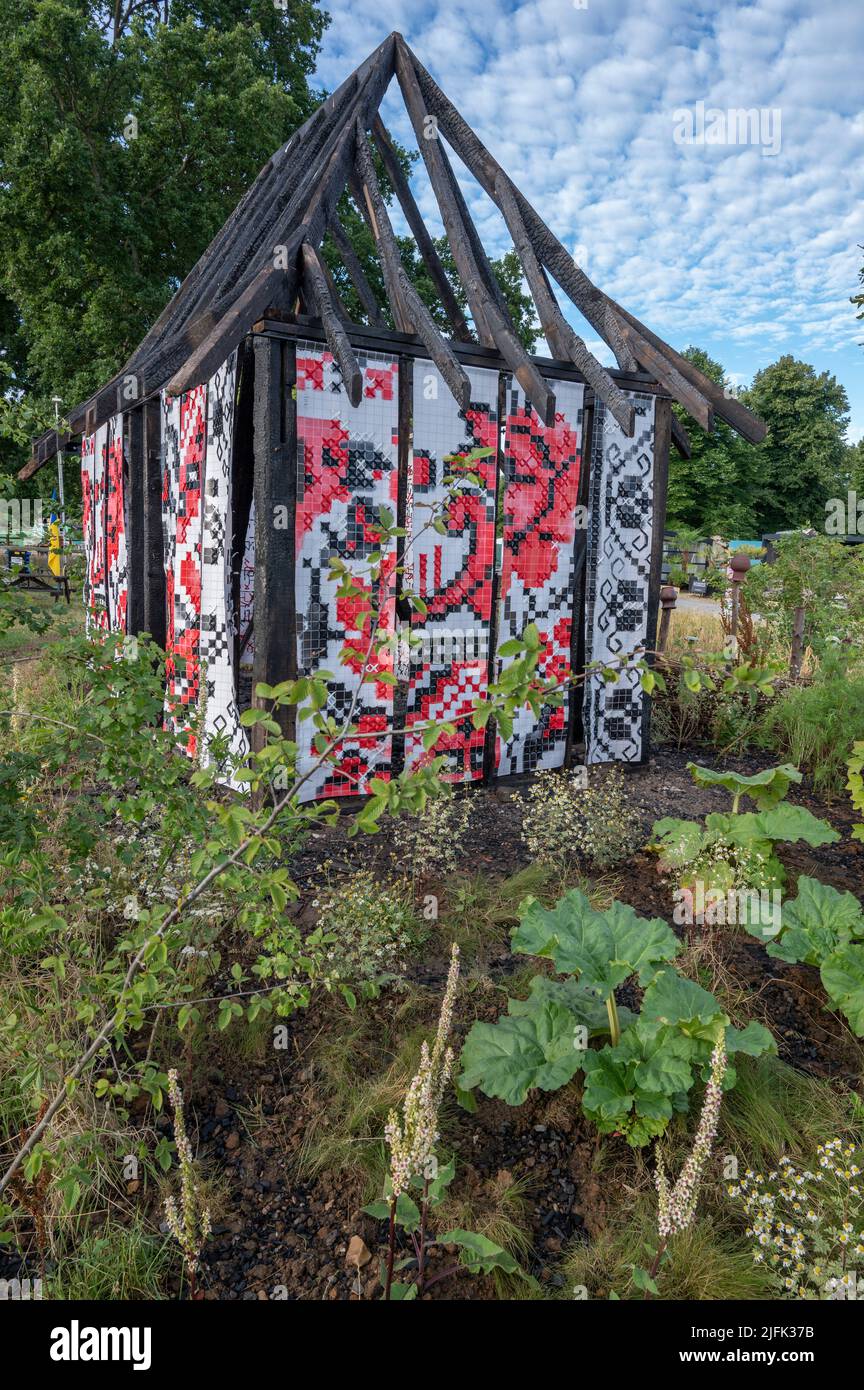Hampton Court Palace, Surrey, Großbritannien. 4. Juli 2022. RHS Hampton Court Palace Garden Festival Pressetag für die größte Blumenschau der Welt, die bis zum 9. Juli 2022 stattfindet. Bild: Global Impact Garden: What does Not Burn Entworfen von Victoria Manoylo und Carrie Preston ist eine Destillation der ukrainischen Landschaft und Kultur. Es zeigt den Rushnyk, ein besticktes Tuch, das in vielen Ritualen verwendet wird, als Symbol des Lebens und der Identität. Wie eine neue Haut schmücken Rushnyks die Überreste einer verbrannten Hütte, die als Silhouette in der Landschaft steht. Quelle: Malcolm Park/Alamy Live News Stockfoto