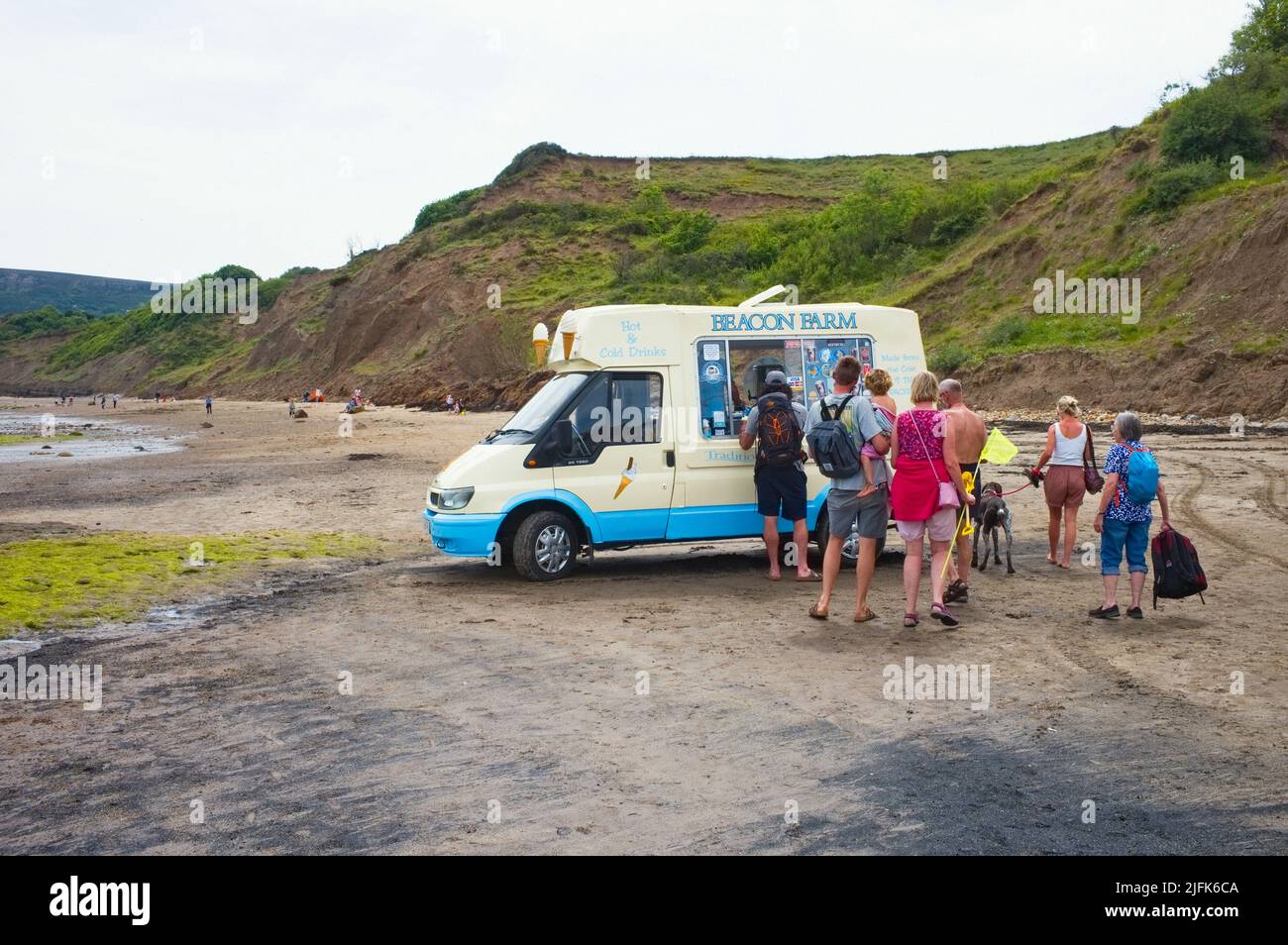 Leute, die sich in einem Van am Strand in Robin Hood's Bay, North Yorkshire, für Eis anstellen Stockfoto