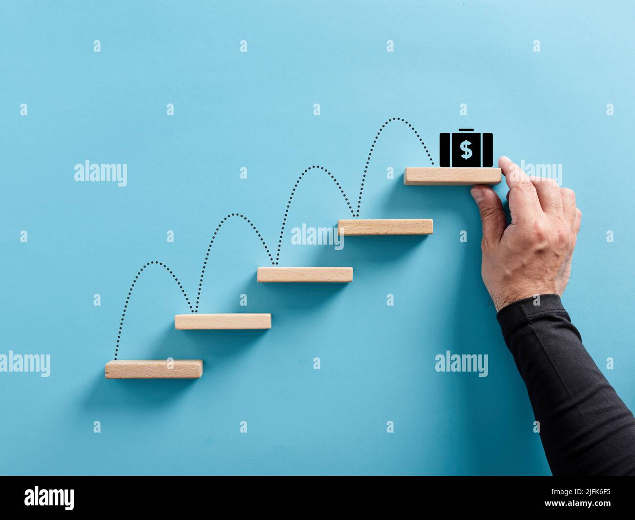 Männliche Hand arrangiert eine hölzerne Blocktreppe mit einer Tasche mit US-Dollar-Geld-Ikone. Gewinn- oder Einkommenswachstum, Wohlstand und Geldverdienen. Stockfoto