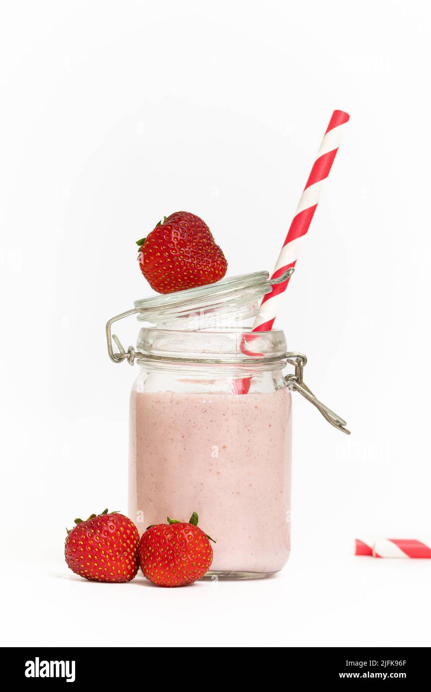Studiofoto eines Erdbeermilchshake oder Smoothie mit rotem Stroh auf weißem Hintergrund Stockfoto
