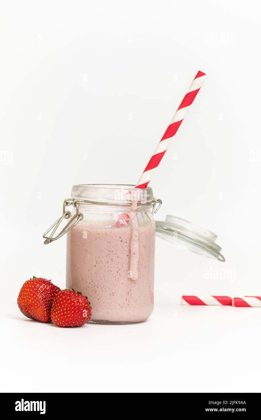 Studiofoto eines Erdbeermilchshake oder Smoothie mit rotem Stroh auf weißem Hintergrund Stockfoto