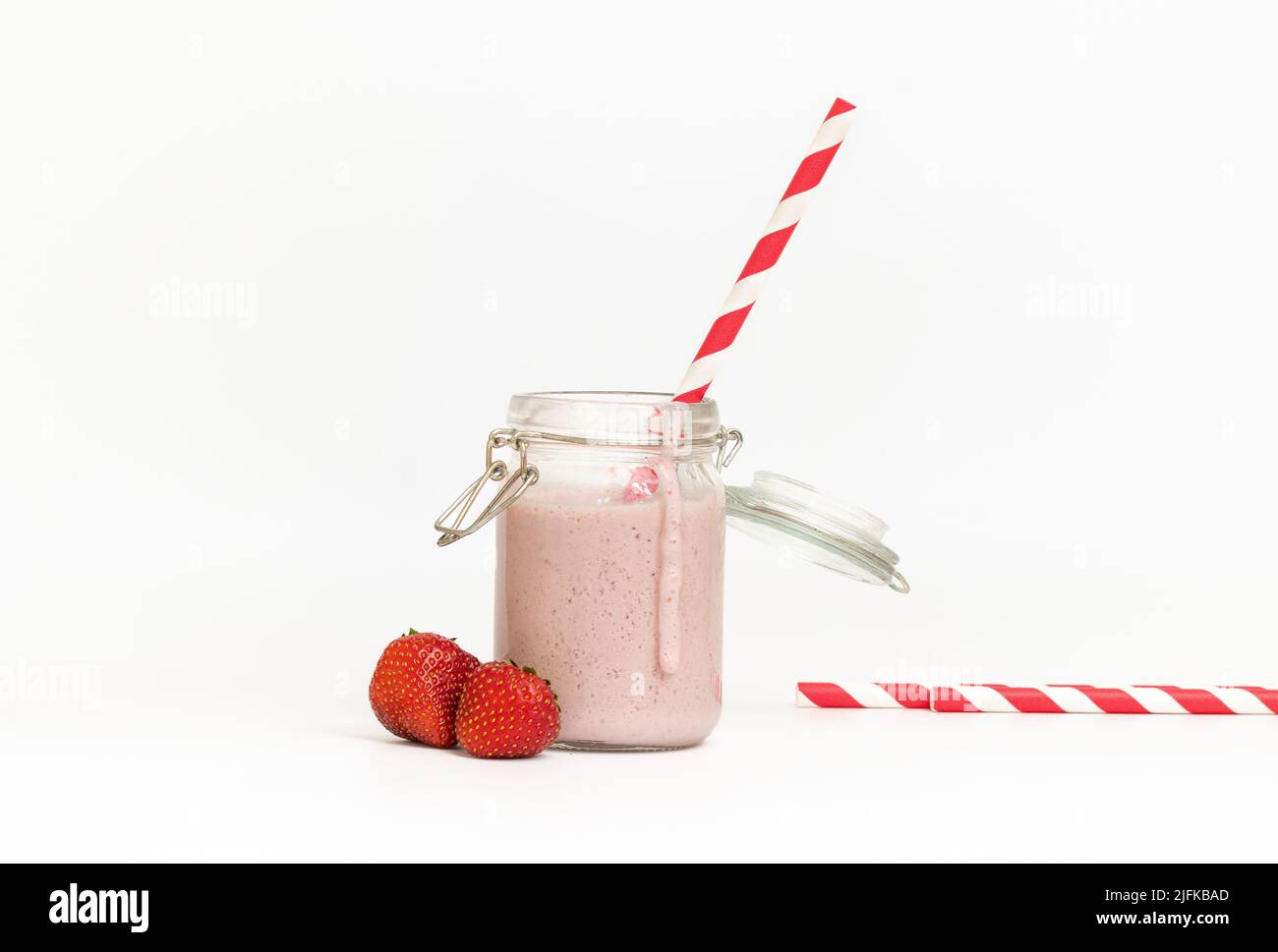 Studiofoto eines Erdbeermilchshake oder Smoothie mit rotem Stroh auf weißem Hintergrund Stockfoto