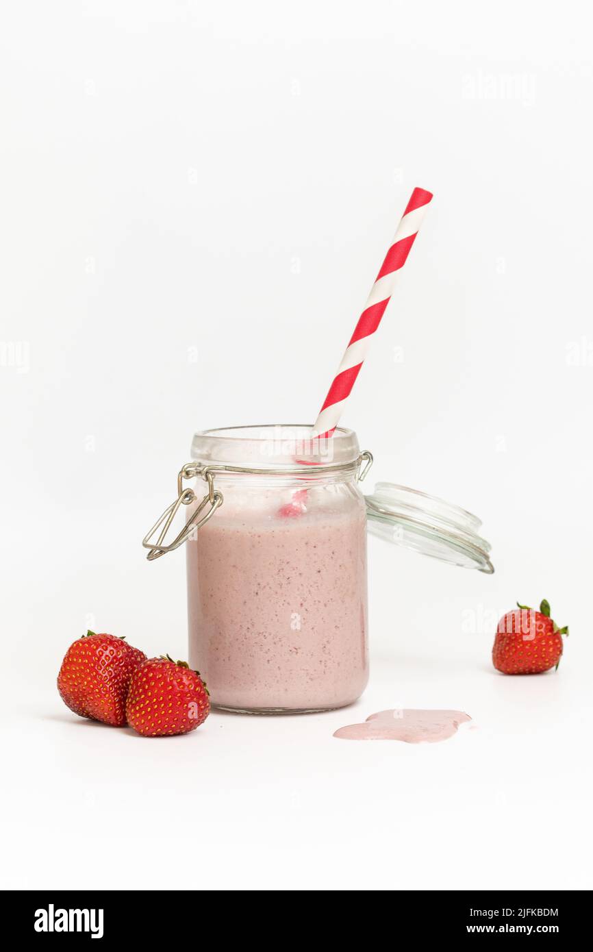 Studiofoto eines Erdbeermilchshake oder Smoothie mit rotem Stroh auf weißem Hintergrund Stockfoto