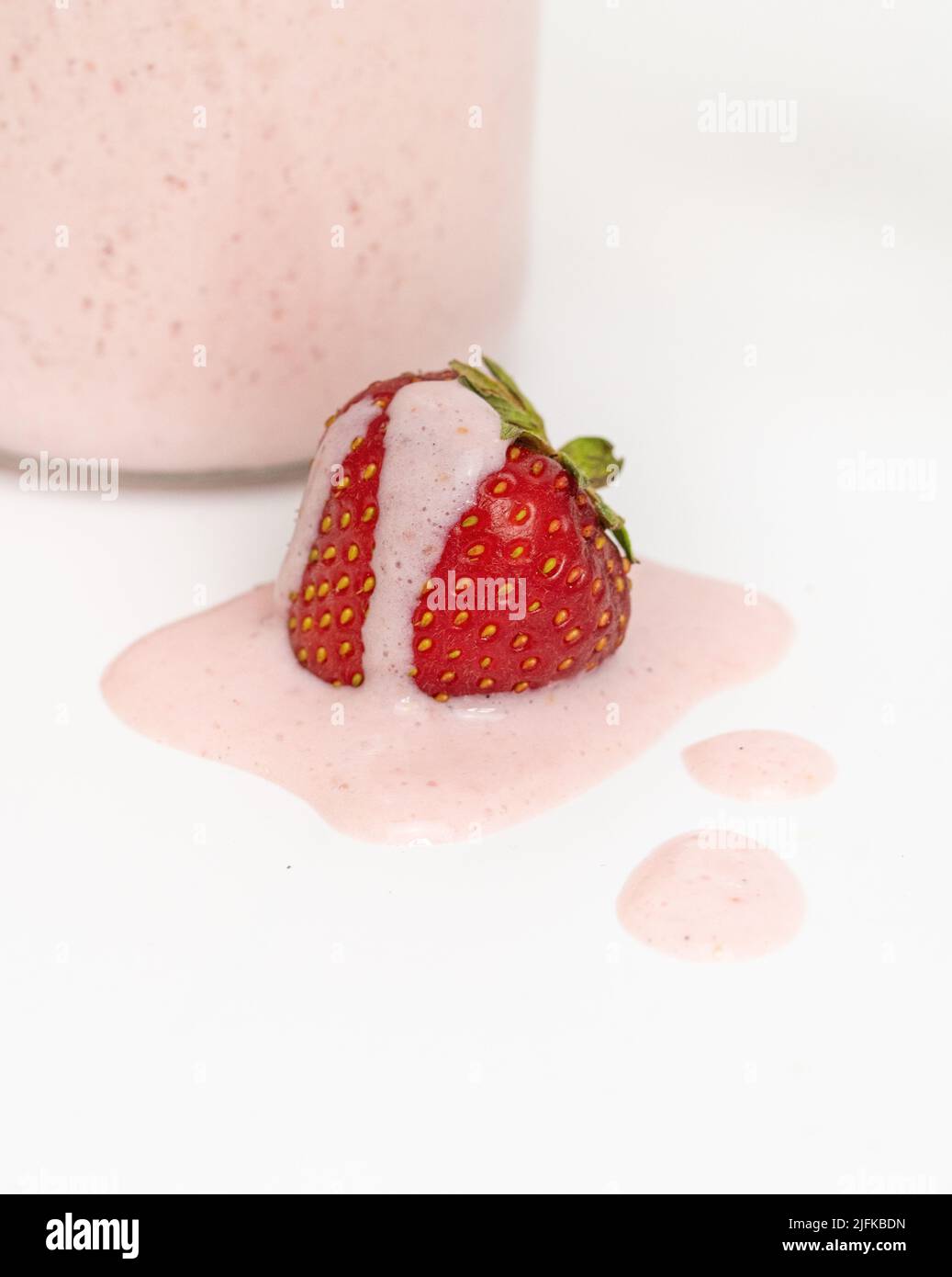 Studiofoto einer Erdbeere, die mit Milchshake oder Smoothie bedeckt ist Stockfoto