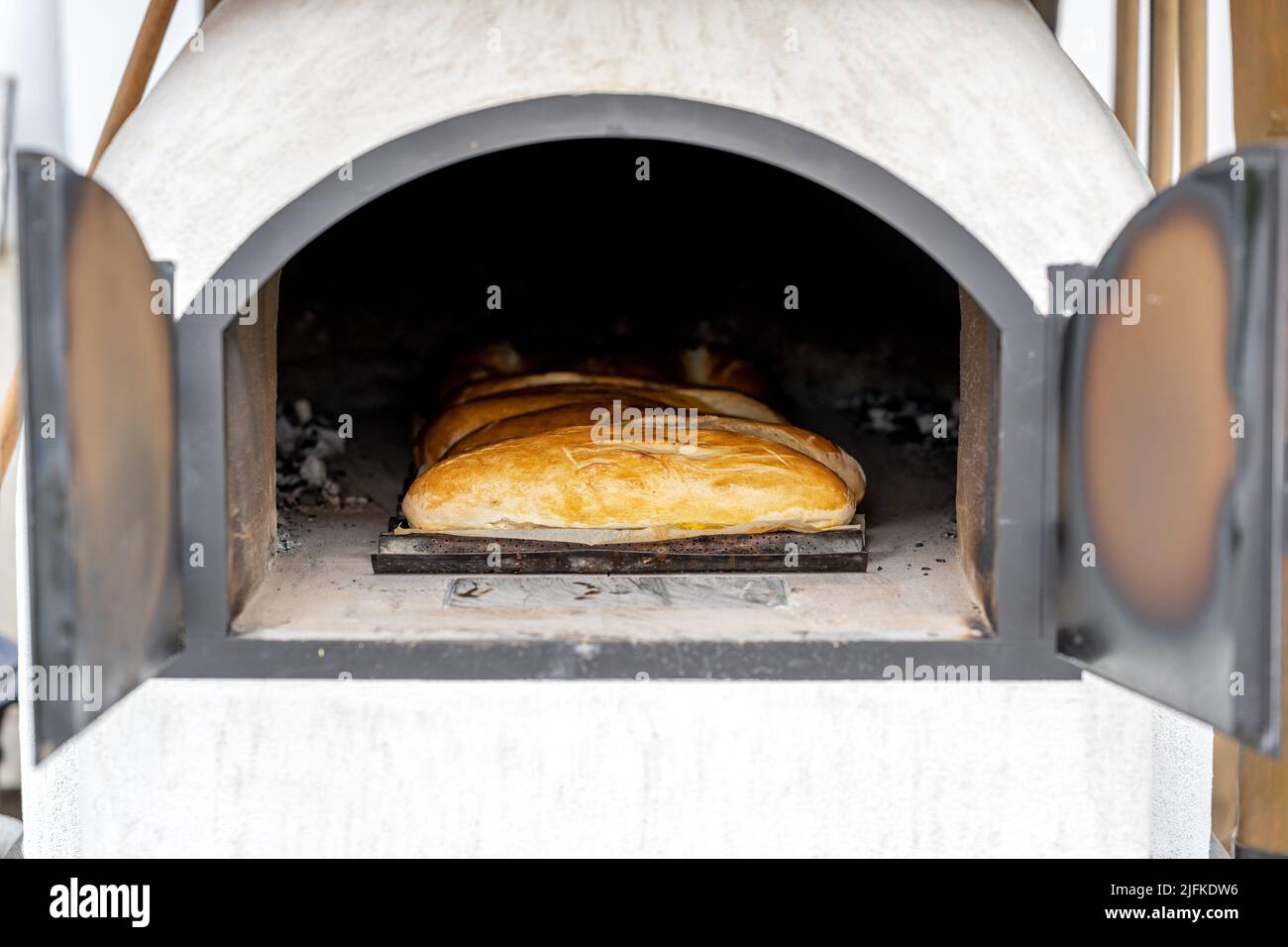 Sehen Sie durch die offene Feuertür in einen alten Backofen auf dem Land, während die Brote gebacken werden. Stockfoto