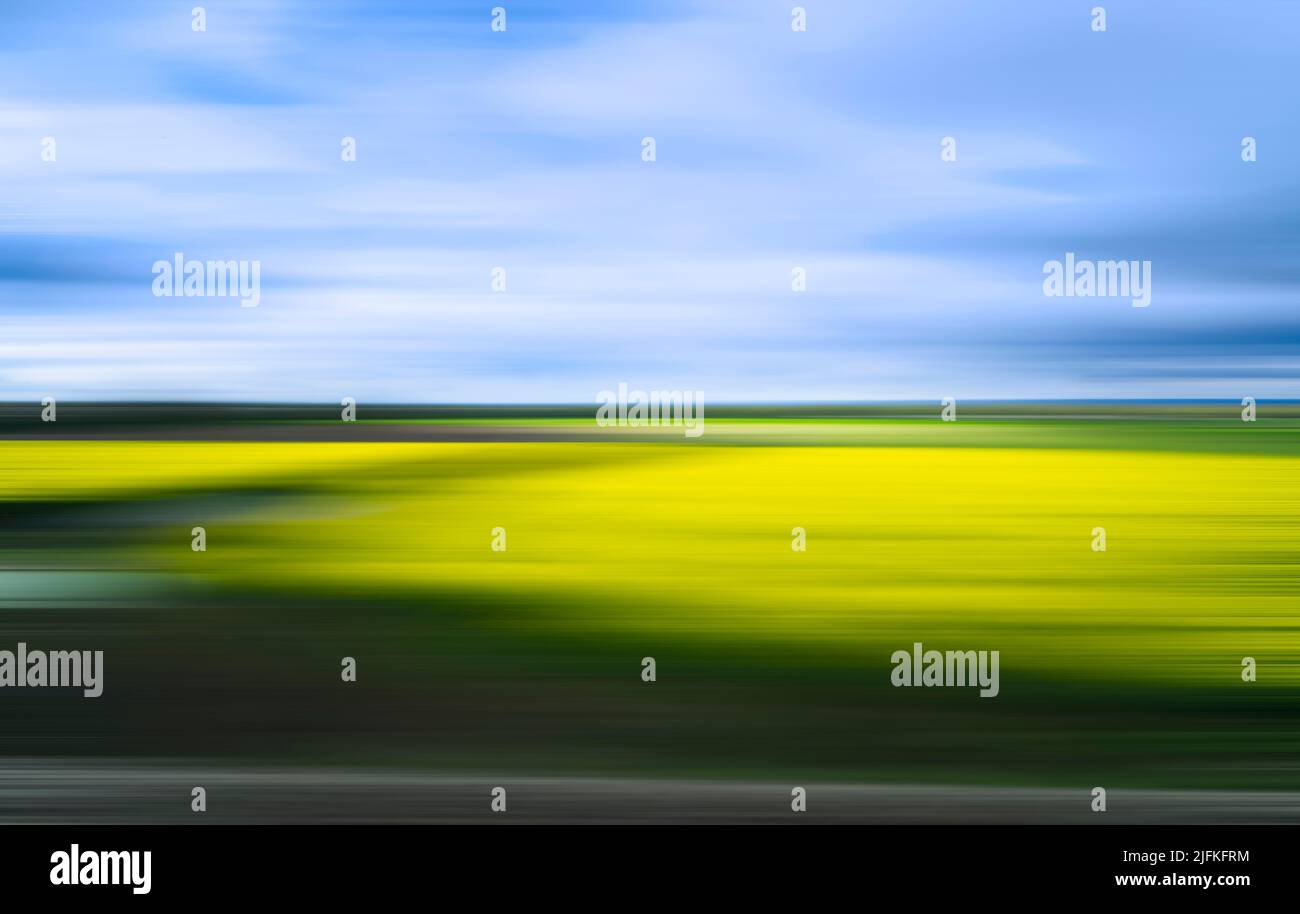 Verschwommenes und erschüttertes Bild einer Landschaft in Grün-, Gelb- und Blautönen, das als Vorlage oder Hintergrund verwendet werden kann. Stockfoto