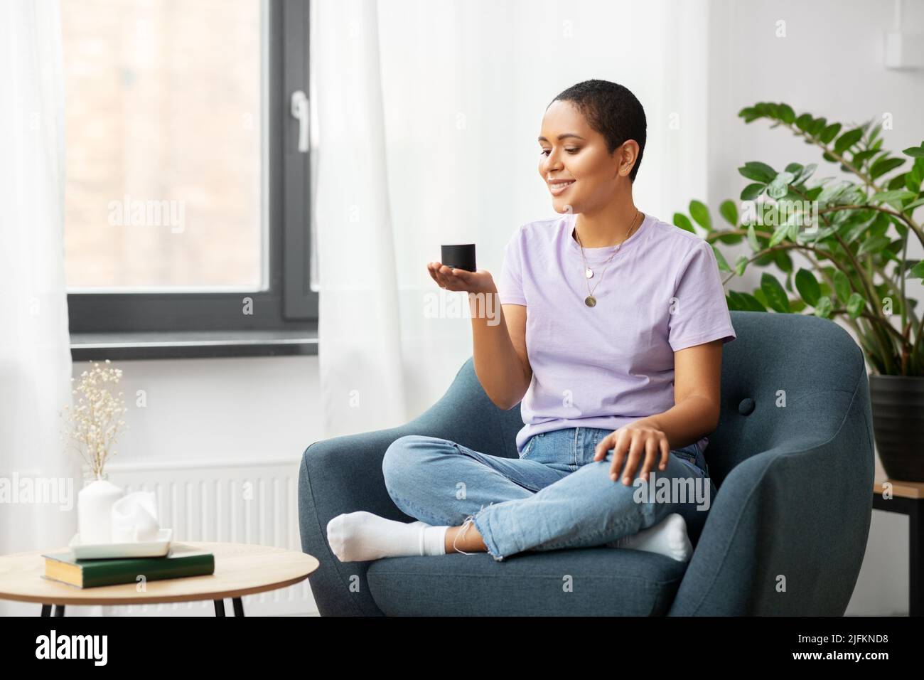 afroamerikanische Frau mit intelligentem Lautsprecher zu Hause Stockfoto