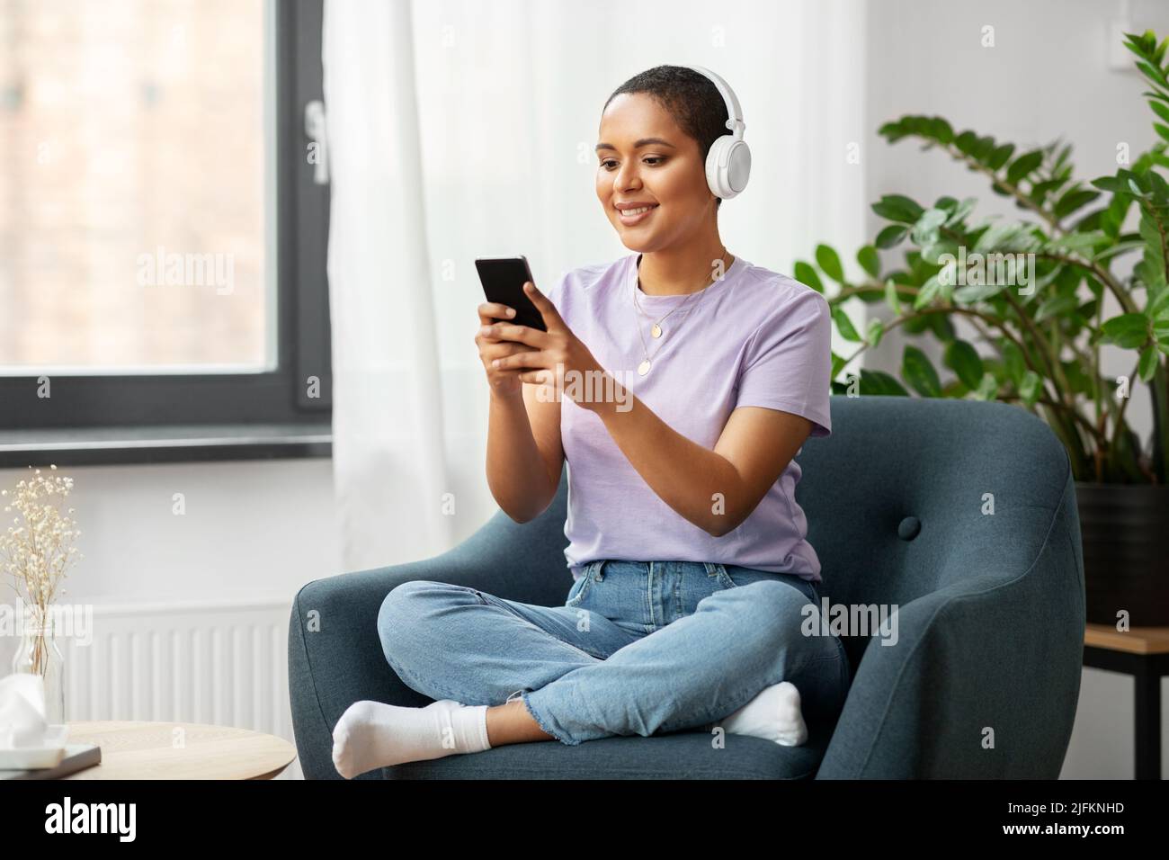 Frau mit Smartphone, die zu Hause Musik hört Stockfoto