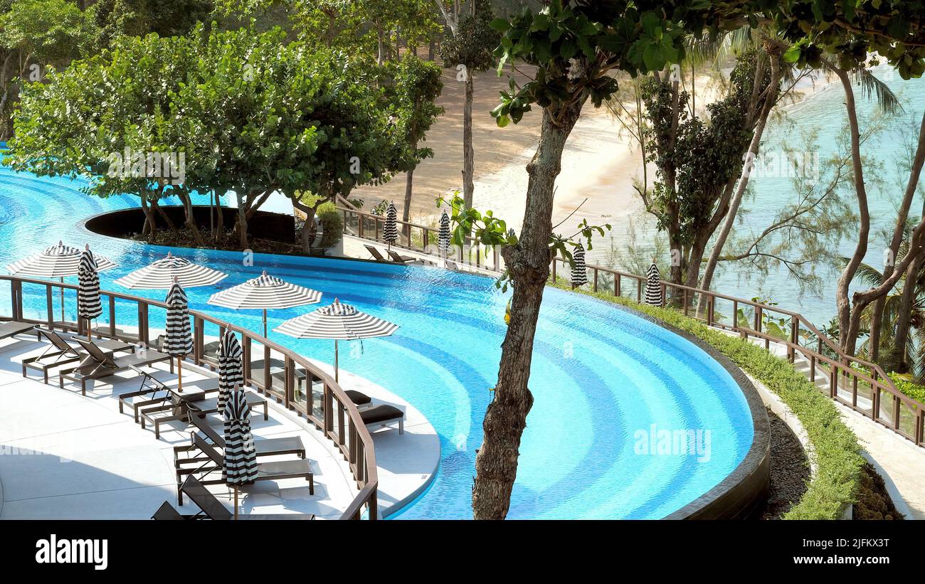 Sonnenliegen mit Sonnenschirmen oder Sonnenschirmen in der Nähe eines wunderschönen Pools in einem modernen tropischen Luxusresort. Konzept von Reise, Reise und Sommerurlaub in Stockfoto