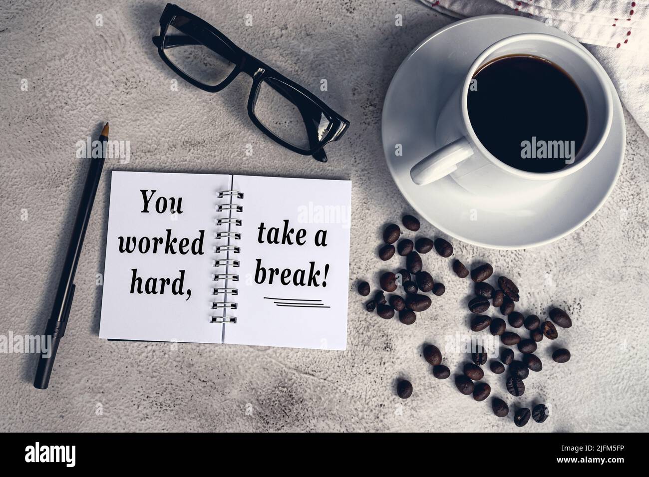Inspirierendes Zitat auf Notizblock mit Kaffee und Kaffee auf weißem Schreibtisch - Sie haben hart gearbeitet, machen Sie eine Pause. Stockfoto