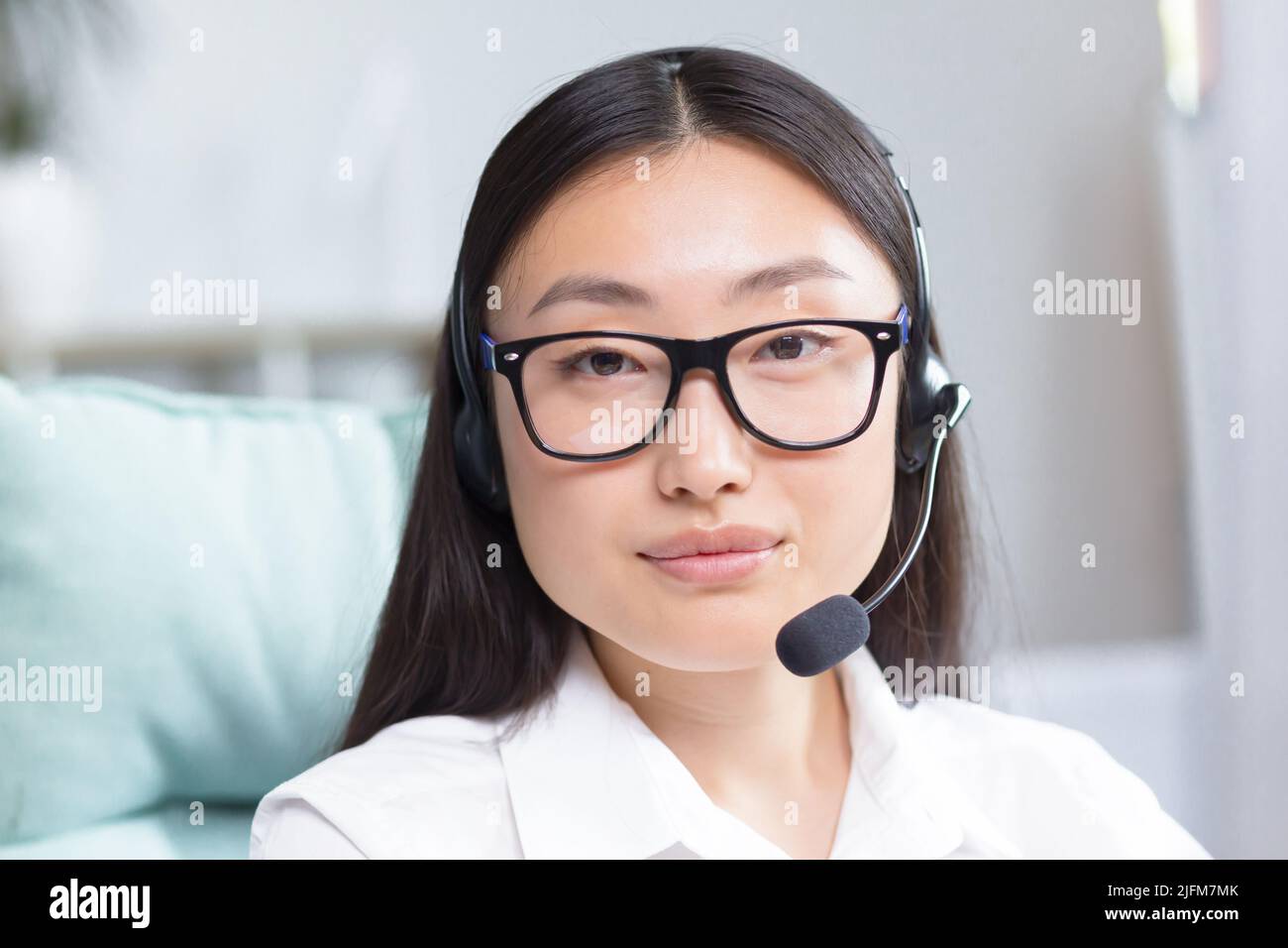 Nahaufnahme eines Porträtfotos von einer asiatischen Callcenter-Mitarbeiterin und einem Mitarbeiter des technischen Supports, die die Kamera anschaut und lächelt und das Headset für Videoanruf verwendet. Stockfoto