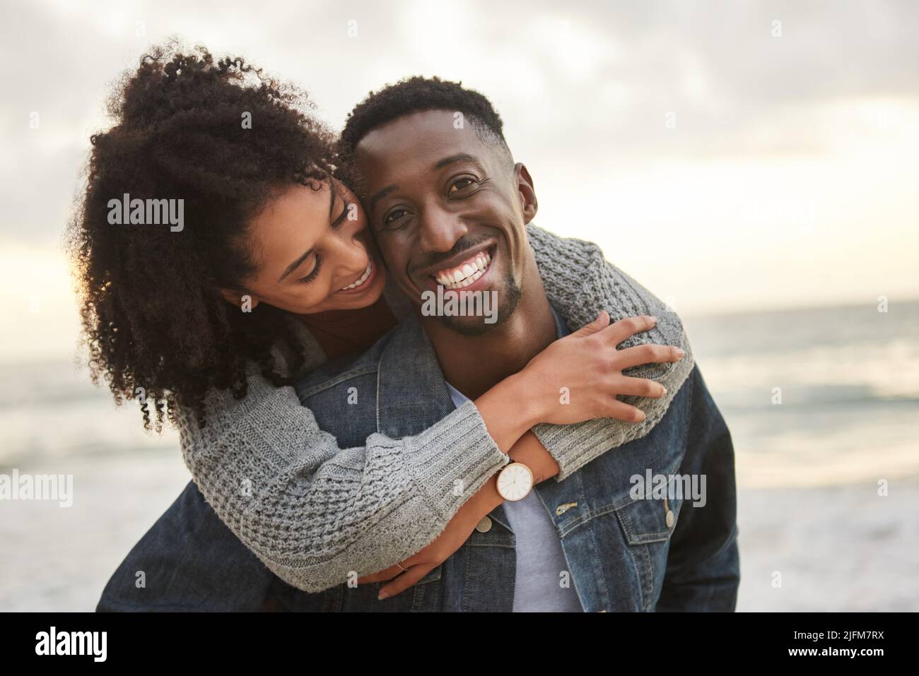 Lächelndes junges multiethnisches Paar, das einen lustigen Nachmittag am Strand hat Stockfoto