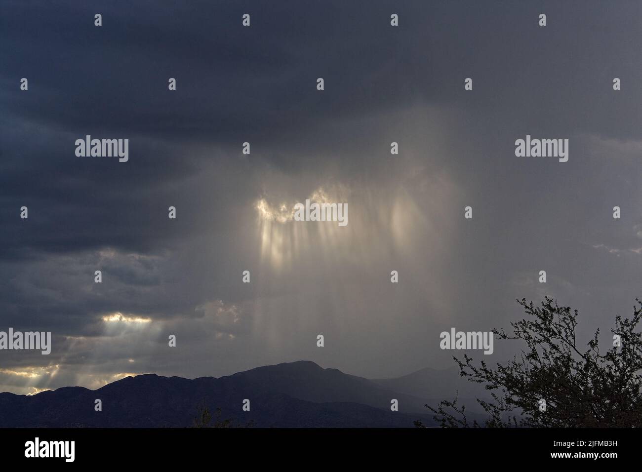 Gewitterwolken über den Bergen mit einstrahlenden Sonnenstrahlen. Stockfoto