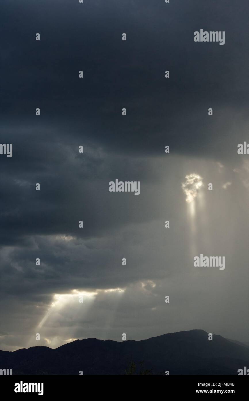 Gewitterwolken über den Bergen mit einstrahlenden Sonnenstrahlen. Stockfoto