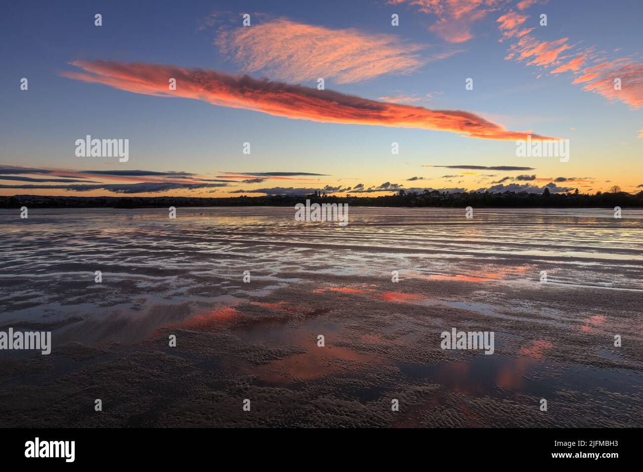 Bei Ebbe spiegelten sich im nassen Sand eines Hafens Sonnenwolken Stockfoto