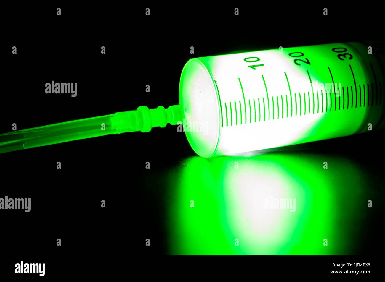 Medizinische Spritze mit legendärem grünen Impfstoff gegen Corona-Virus und Monkeypox auf dunklem Hintergrund. Medizinische Behandlung. Stockfoto