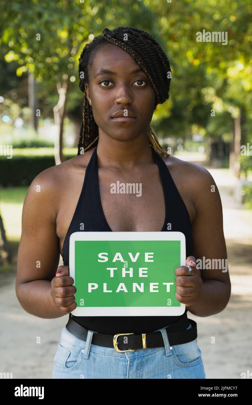 Junger afroamerikanischer Aktivist mit einer „Save the Planet“-Botschaft auf einem Tablet-Bildschirm. Stockfoto