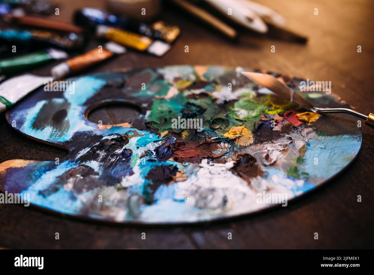 Palette in Farbe und ein Palettenmesser auf einem Holztisch. Stockfoto