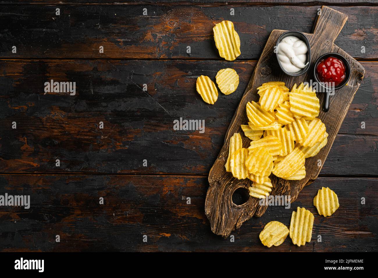 Gewellter, fettreduzierter Chip auf altem dunklen Holztischhintergrund, Draufsicht flach liegend, mit Platz für Text Stockfoto