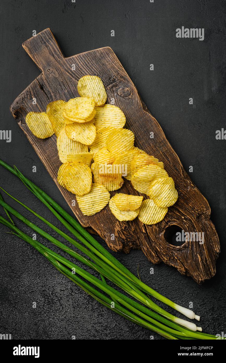 Gewellter, fettreduzierter Chip auf schwarzem, dunklem Steintisch-Hintergrund, Draufsicht flach liegend Stockfoto