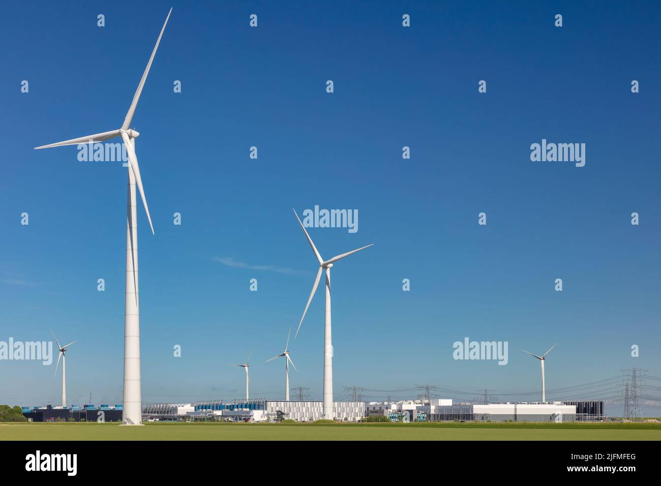 Eemshaven, Niederlande - 2. Juni 2022: Blick auf ein Google-Rechenzentrum mit umliegenden Windenergieanlagen vor einem klaren blauen Himmel in Eemshaven Stockfoto