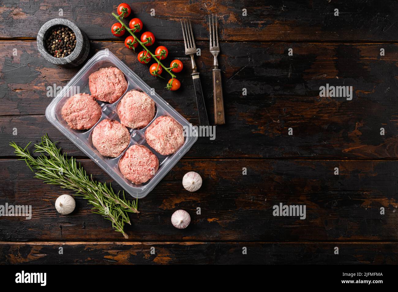 Rohe frische Hühnerschnitzel in durchsichtigem Plastikbehälter, auf altem dunklen Holztischhintergrund, Draufsicht flach liegend, mit Platz für Text Stockfoto