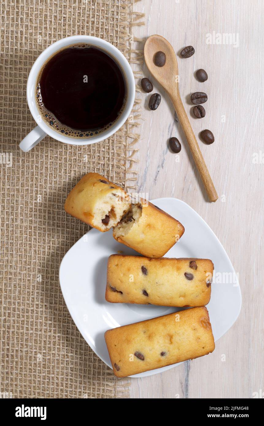 Tasse Kaffee und Kuchen mit Schokoladenstückchen auf Holztisch, Draufsicht Stockfoto